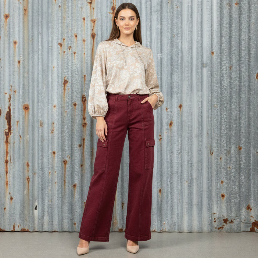Maroon pants and a patterned top on a wooden floor with boxes in the background