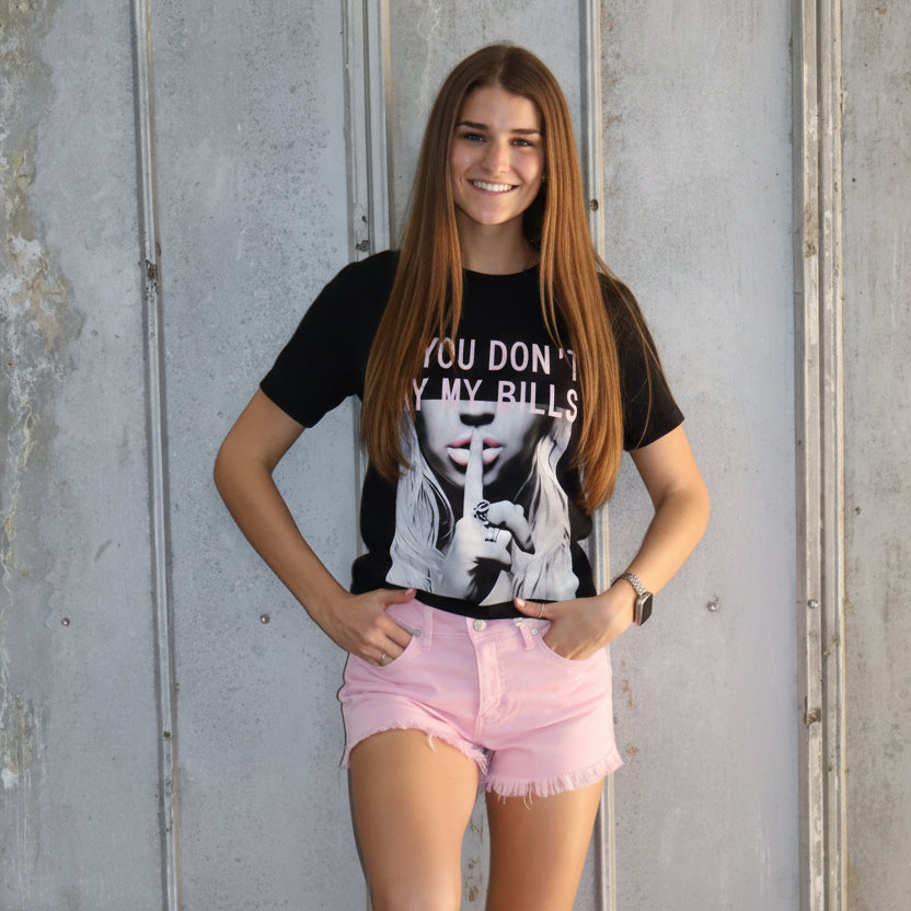 Person wearing a black t-shirt with graphic design and pink shorts, standing on a metallic surface.