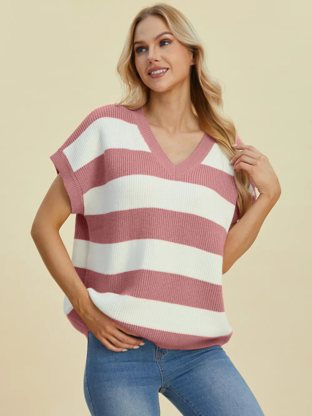 Woman wearing a pink and white striped sweater against a beige background