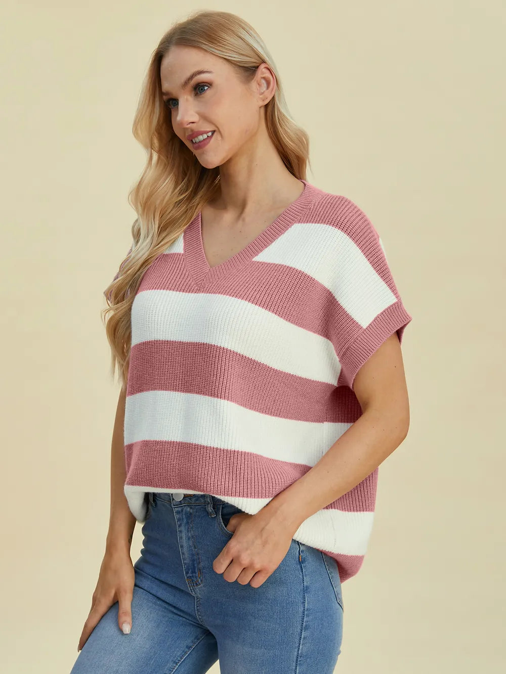 Woman wearing a red and white striped sweater with blue jeans on a beige background