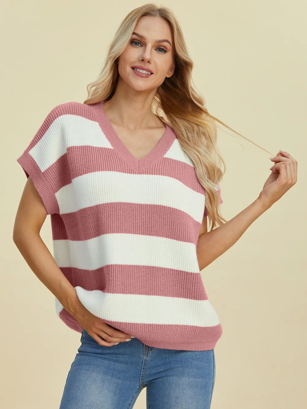 Woman wearing a pink and white striped sweater against a beige background