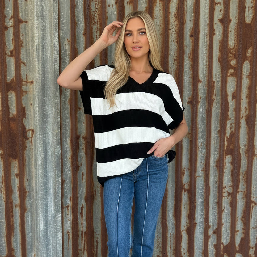 Woman wearing a black and white striped sweater and blue jeans indoors.