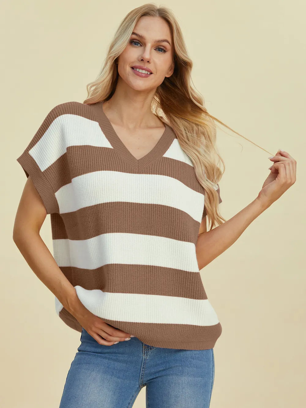 Woman wearing a brown and white striped sweater against a beige background