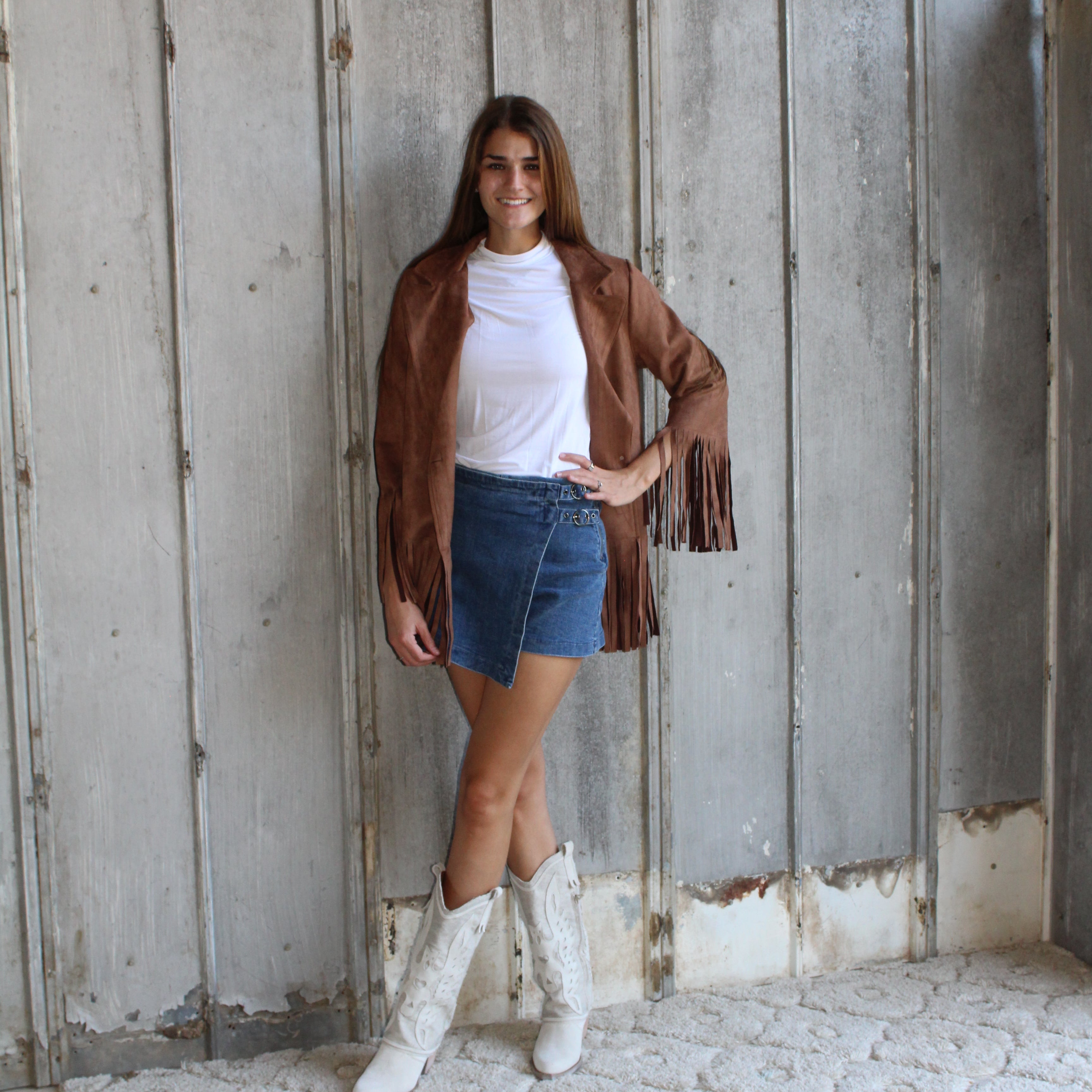 Person wearing a brown leather jacket and white boots on a staircase.