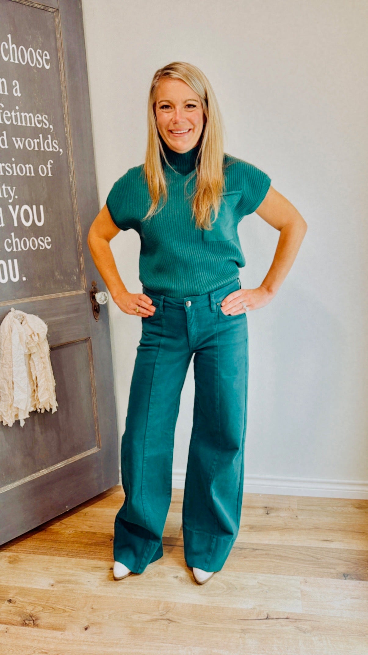 Woman wearing a teal outfit standing in front of a chalkboard with text.