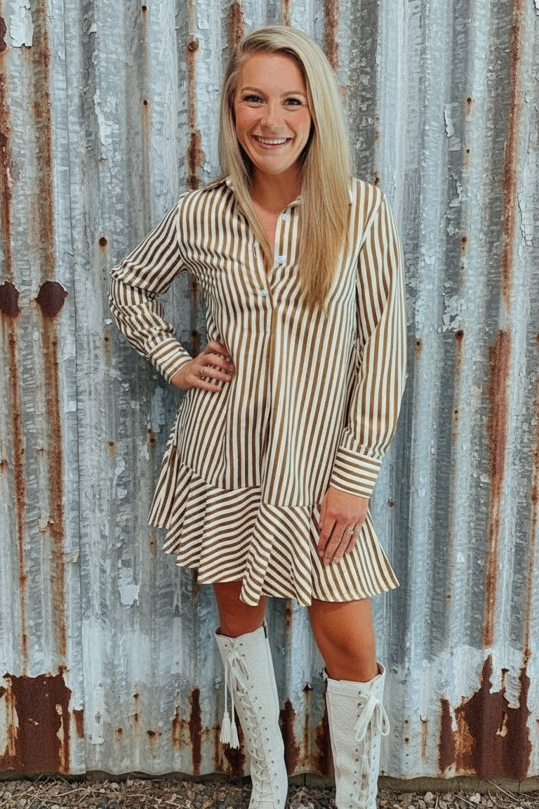 Woman in a striped dress and white lace boots standing in a room with wooden flooring.