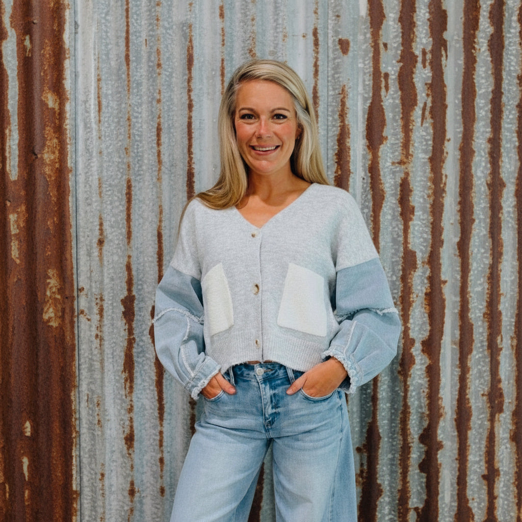 Woman wearing a light blue cardigan and jeans standing in front of a wooden door with text.
