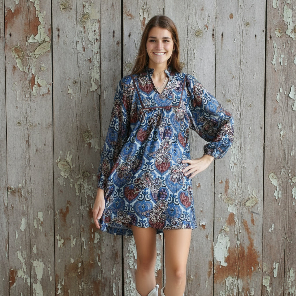 Woman in a patterned dress standing on a metal staircase.