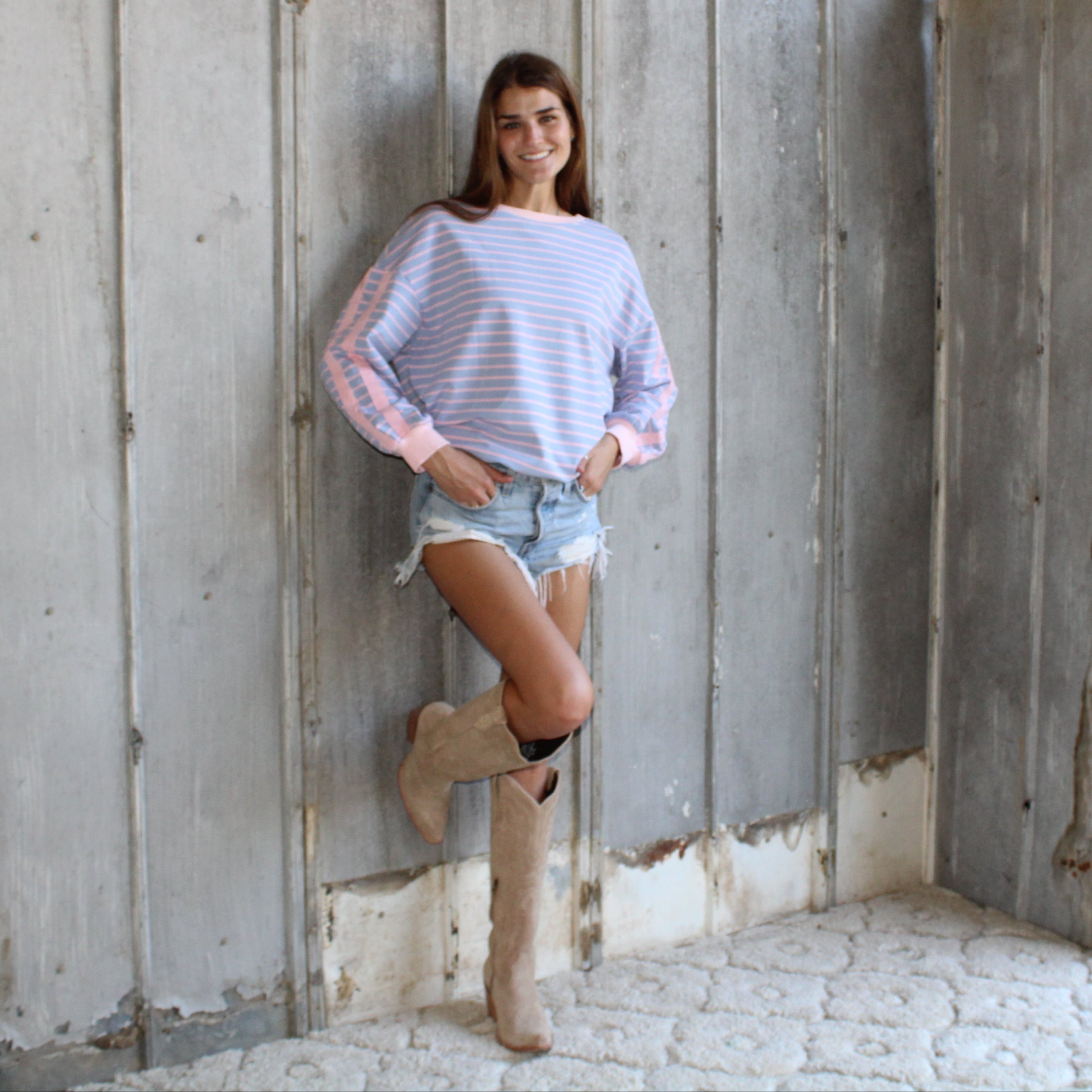 Woman standing against a wooden wall with a rustic outdoor setting