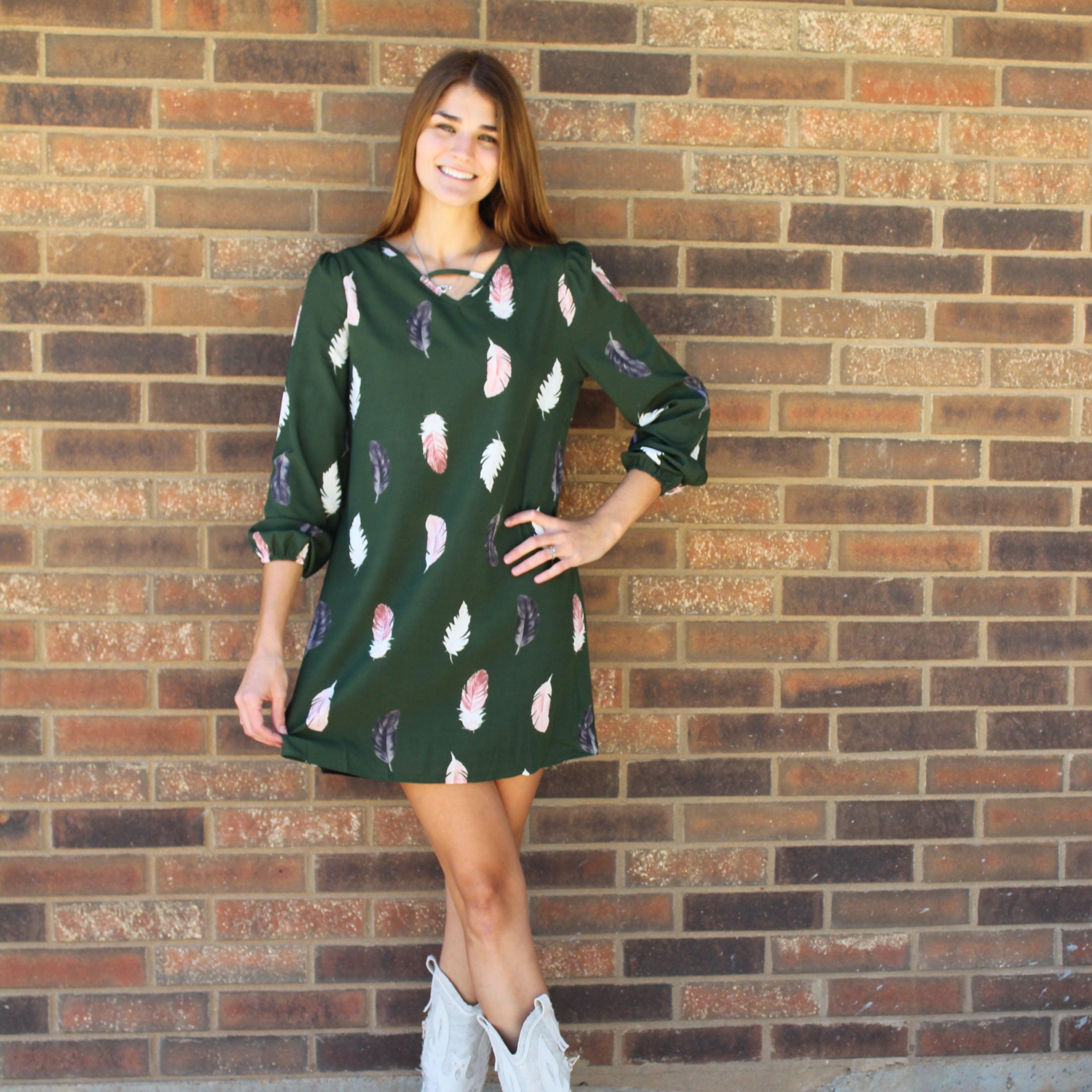 Person wearing a green dress with pink floral patterns on a brick pavement.