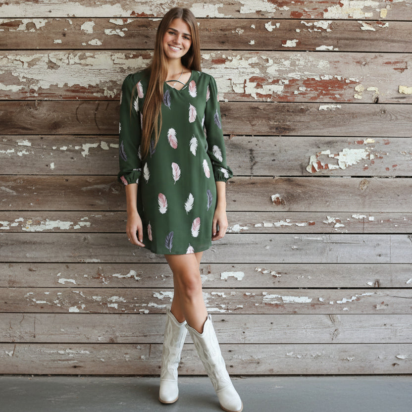 Woman in a green dress with pink patterns standing on a set of stairs.