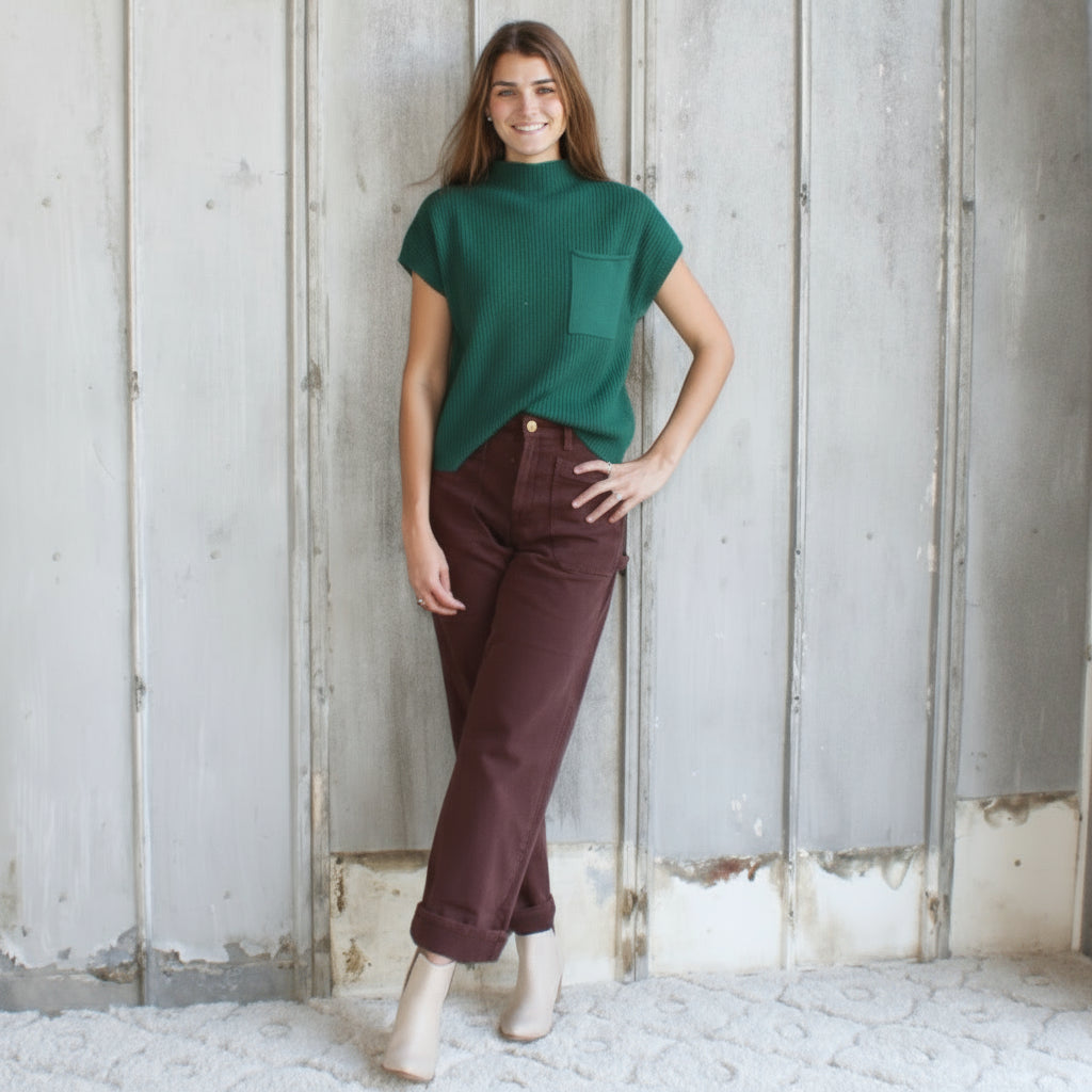 Woman standing in a rustic indoor setting with wooden walls and a textured floor.
