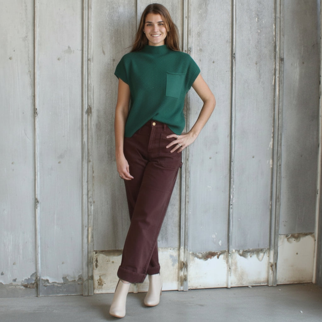 Woman standing in a rustic indoor setting with wooden walls and a textured floor.