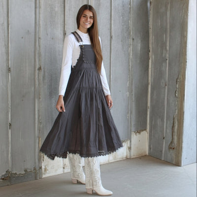 Woman wearing a dark gray dress standing in front of a wooden wall.