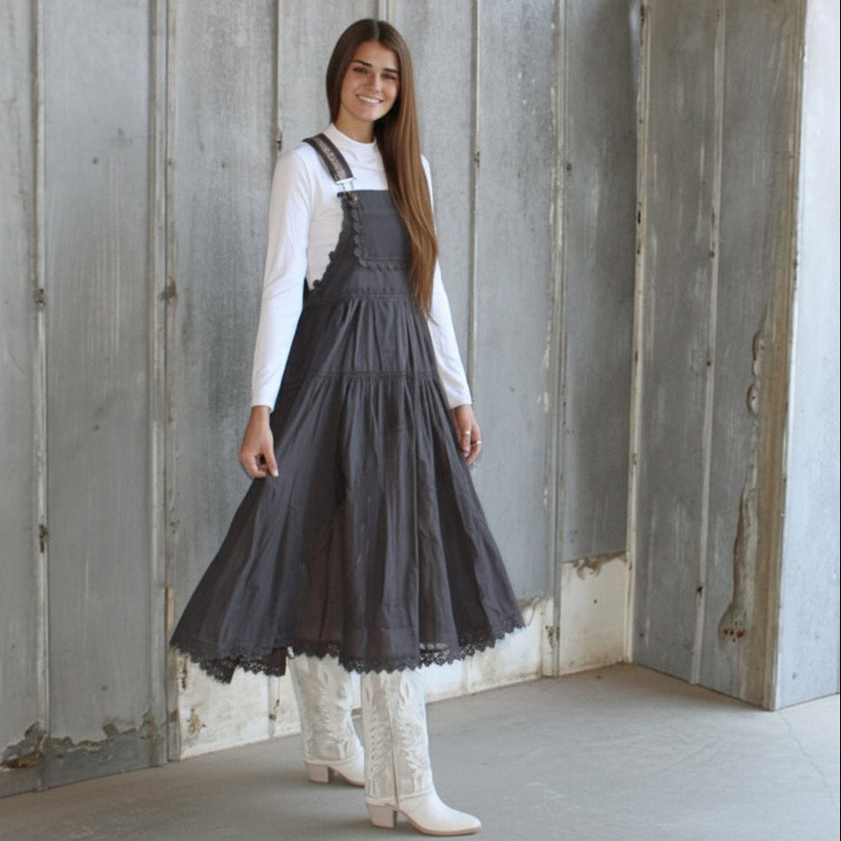 Woman wearing a dark gray dress standing in front of a wooden wall.