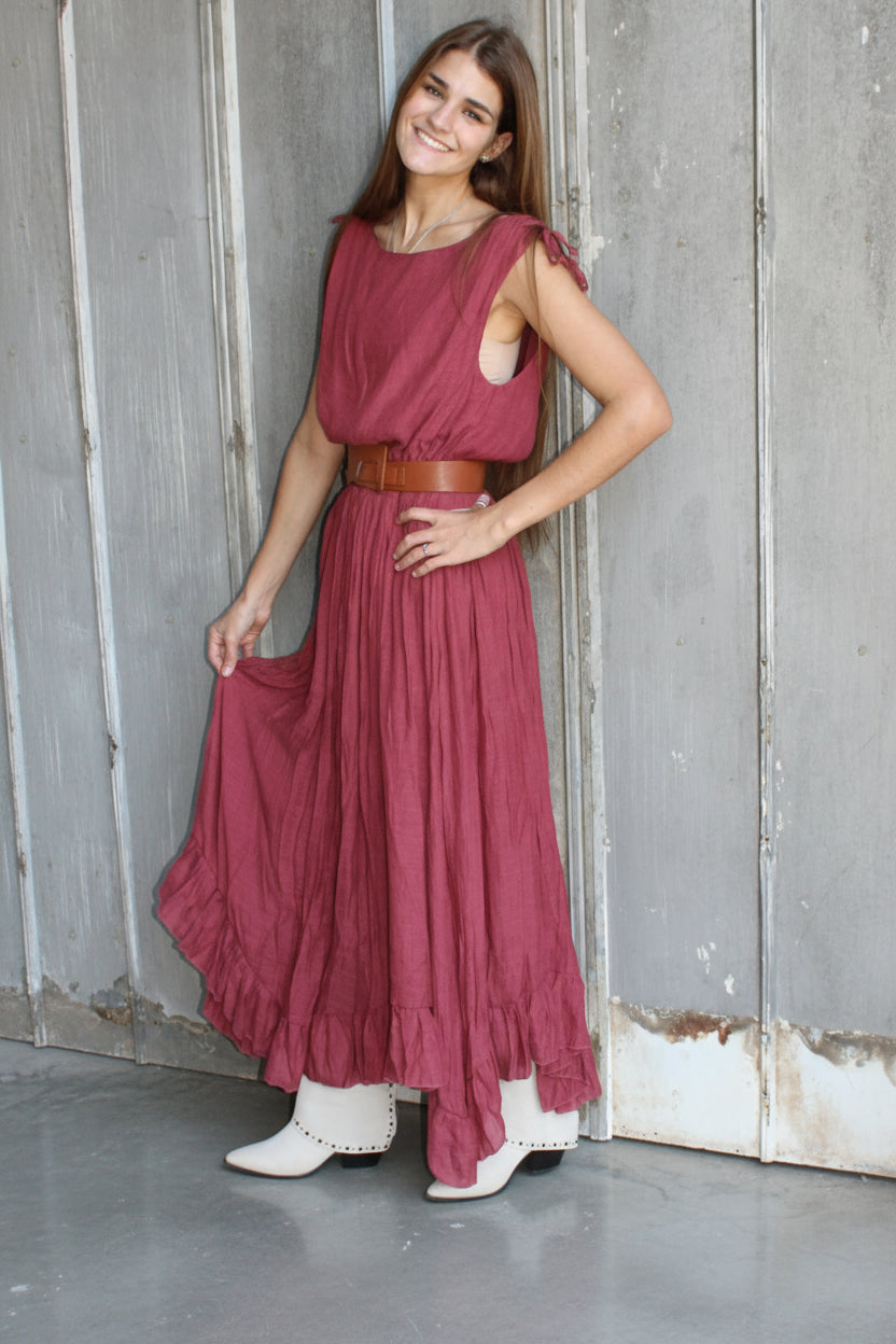 Woman in a burgundy dress standing on a metal staircase against a textured wall.