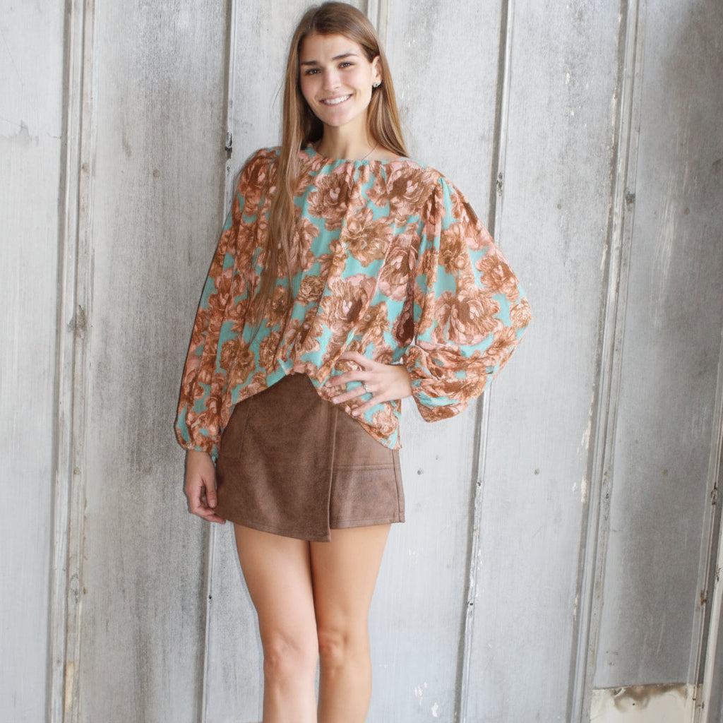 Woman lying on a set of stairs wearing a patterned top and brown skirt.