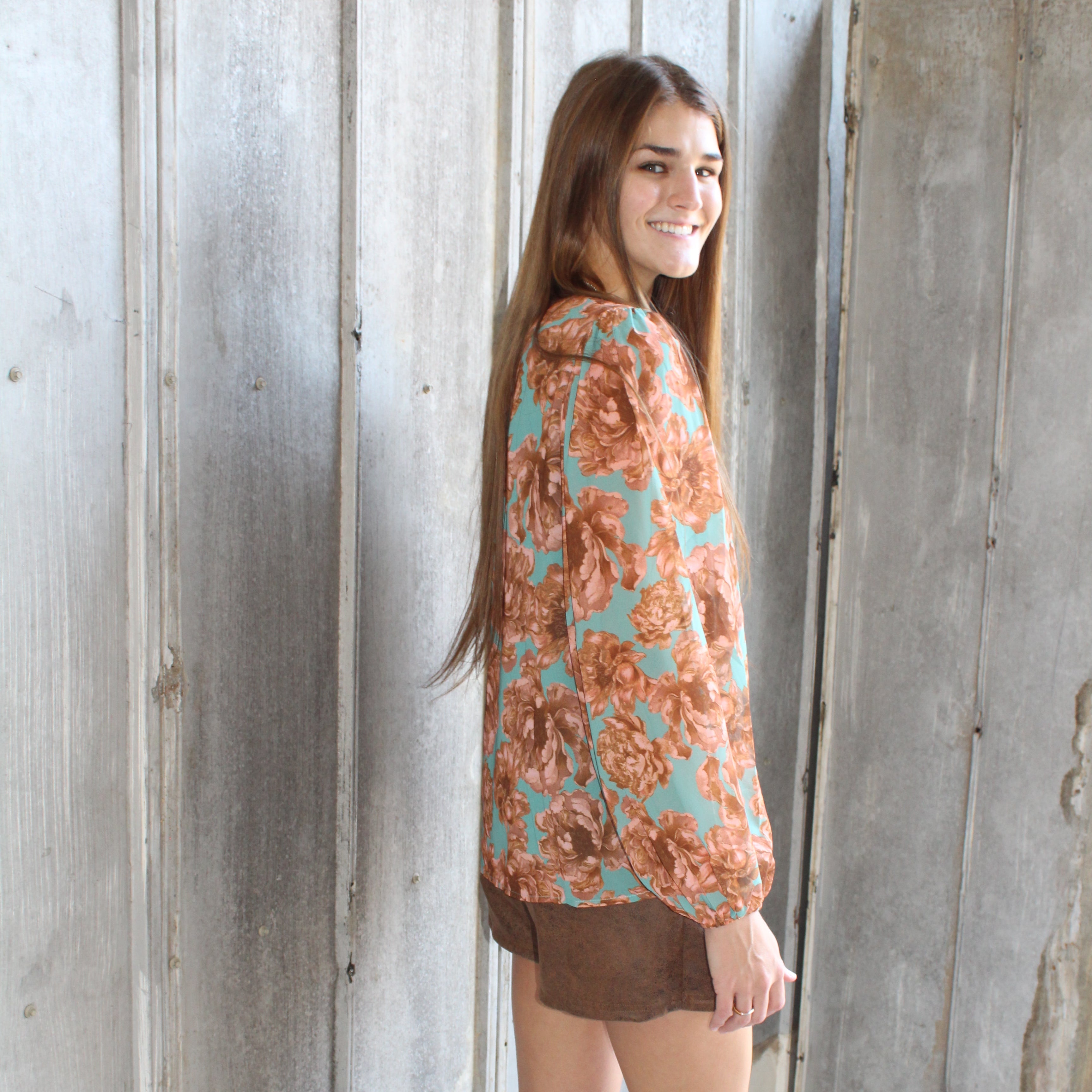 Woman wearing a floral dress standing on a wooden floor.