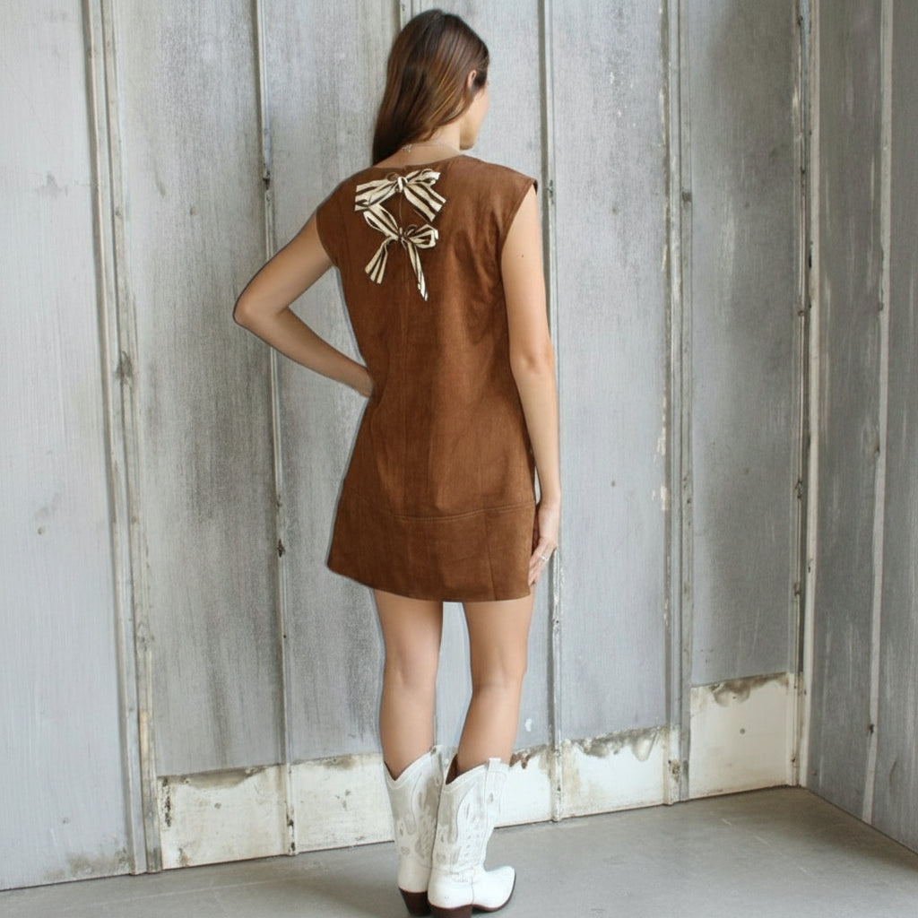 Woman in a brown dress standing on a stone staircase.