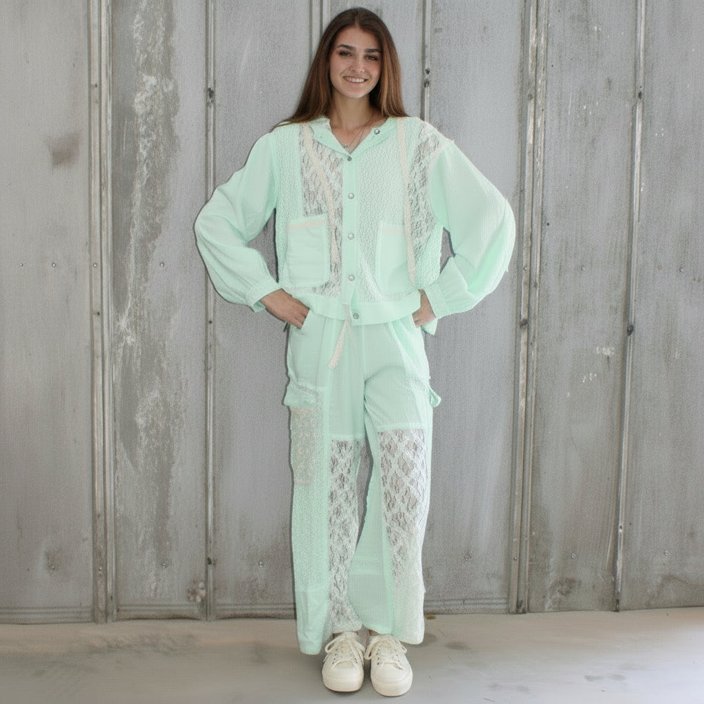 Person wearing a light green outfit standing against a wooden wall.