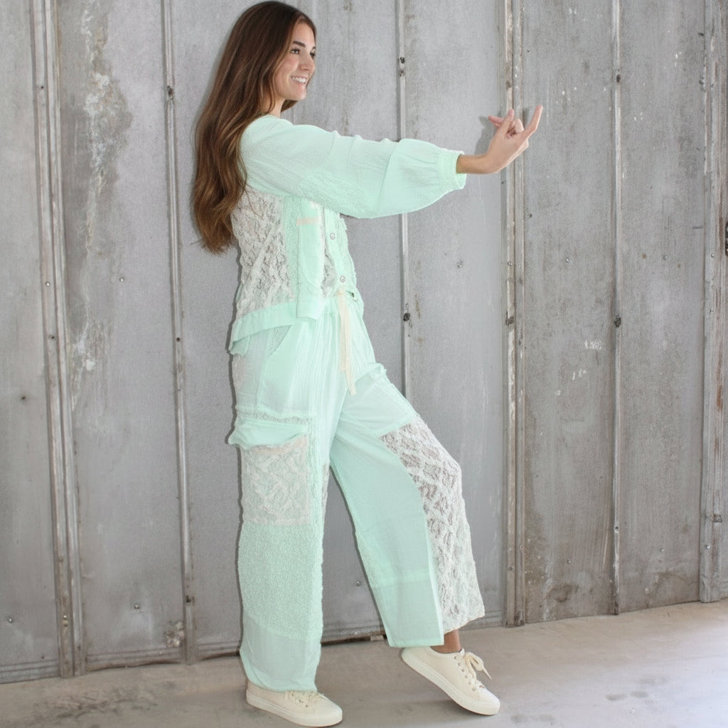 Woman in a light green outfit standing on a wooden floor.