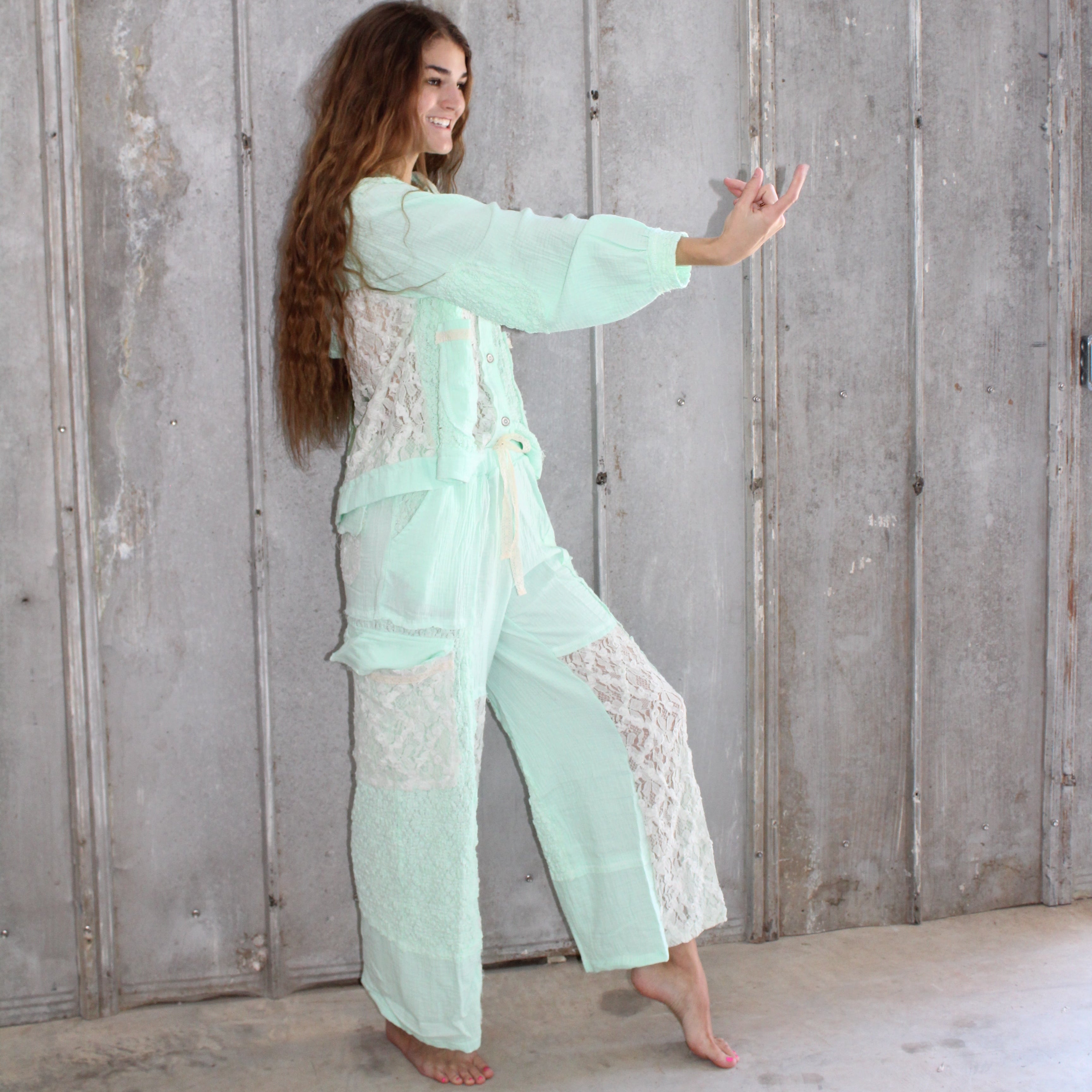 Woman in a light green outfit standing on a wooden floor.