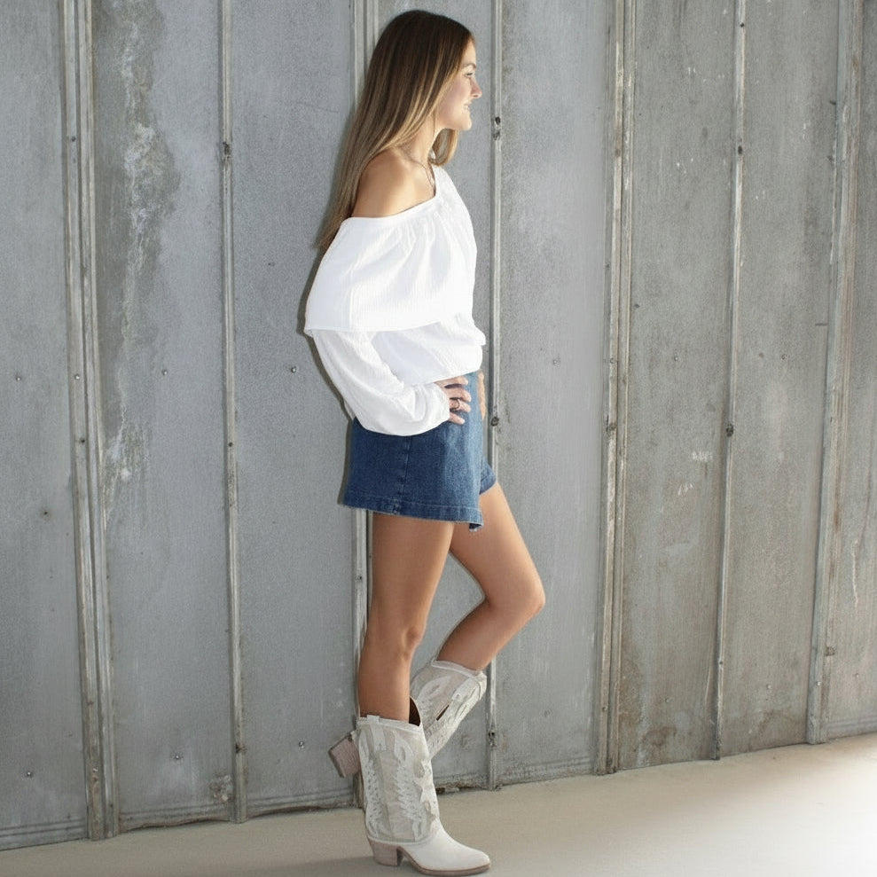 Person lying on a wooden floor against a white wall