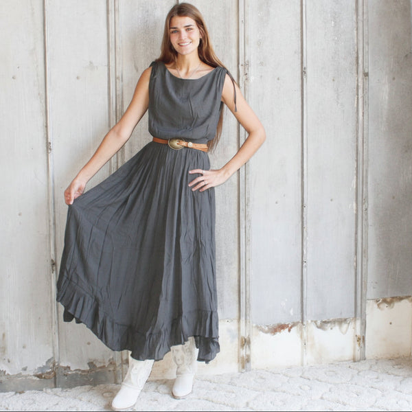 Woman in a gray dress standing in a rustic wooden interior.