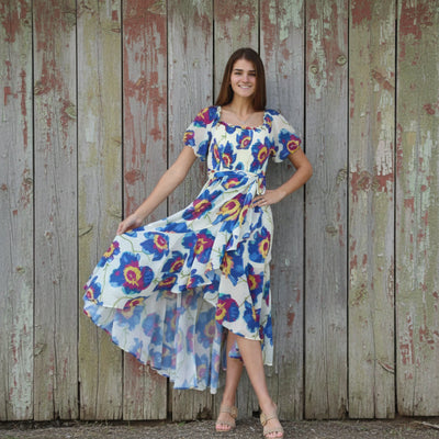 Woman in a floral dress standing against a brick wall