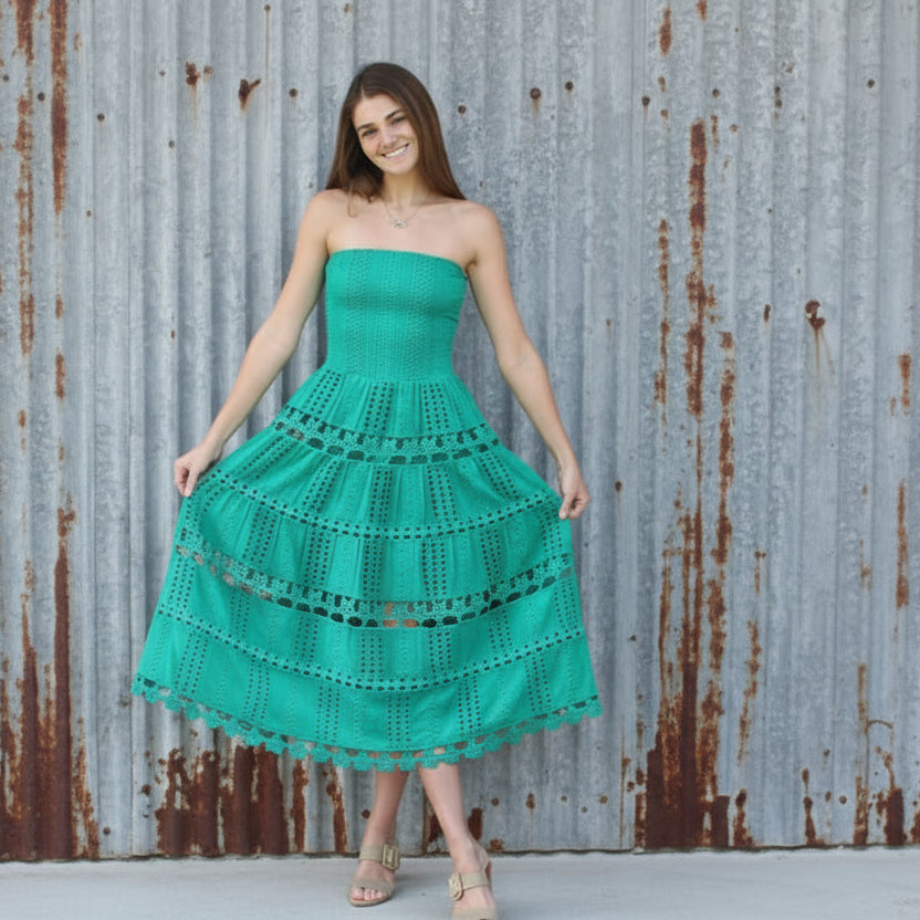 Woman wearing a green dress standing in front of a brick wall.