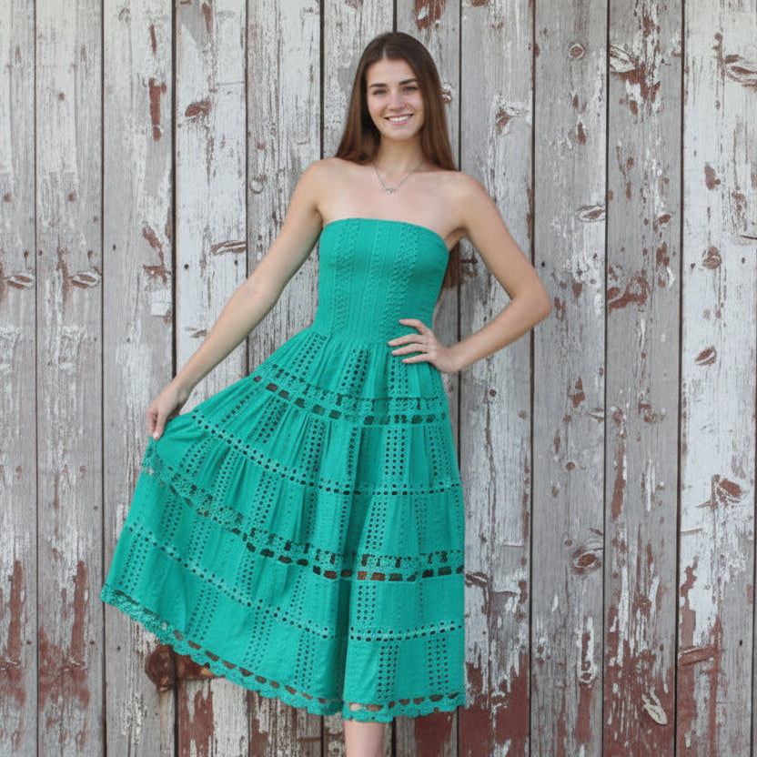 Woman in a teal strapless dress standing against a rustic wooden wall.