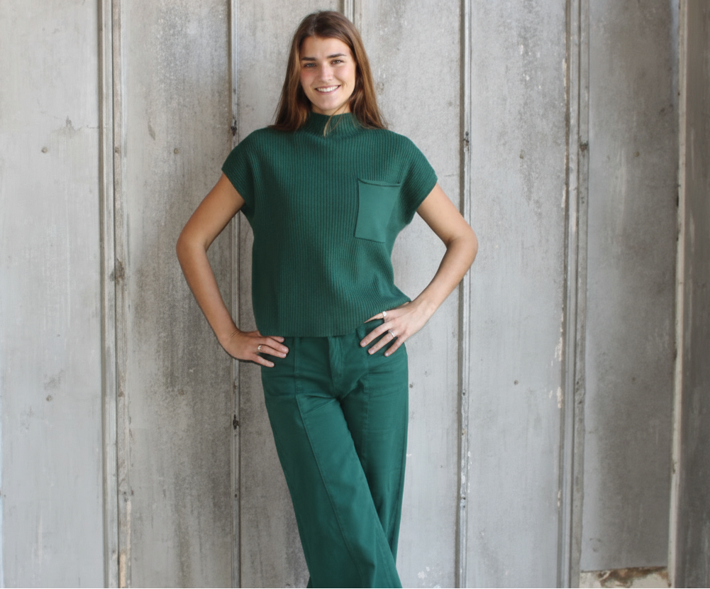 Woman wearing a green scrub set against a wooden background