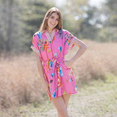 Woman in a colorful dress standing in a field with trees in the background