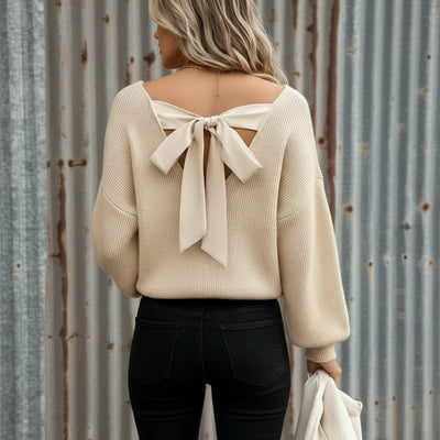 Beige sweater with a bow detail on the back, worn by a person.