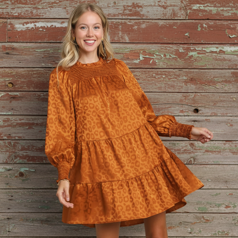 Woman wearing a rust-colored dress with long sleeves and a pattern on a gray background