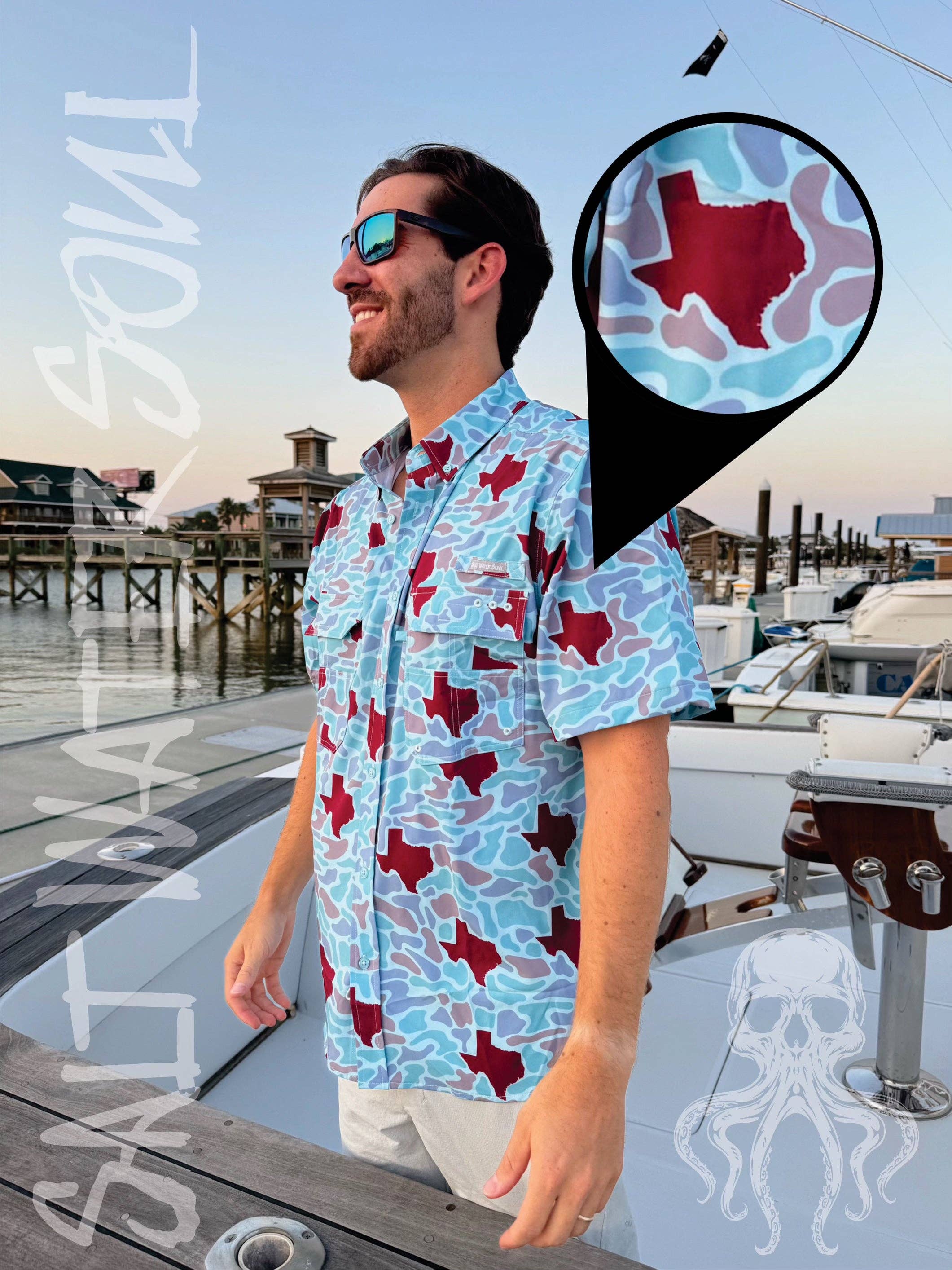 Man wearing a blue shirt with red Texas shapes on a dock with boats and water in the background.