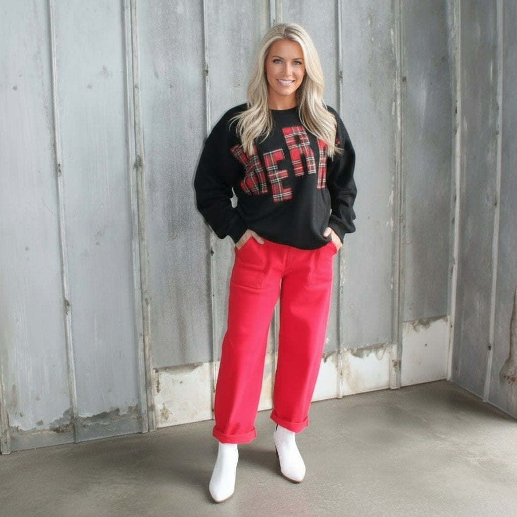 Person wearing a black hoodie with red text and bright pink pants standing on a wooden staircase.
