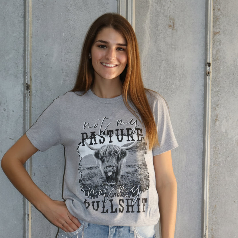 Woman wearing a graphic t-shirt and denim shorts standing on a concrete floor.
