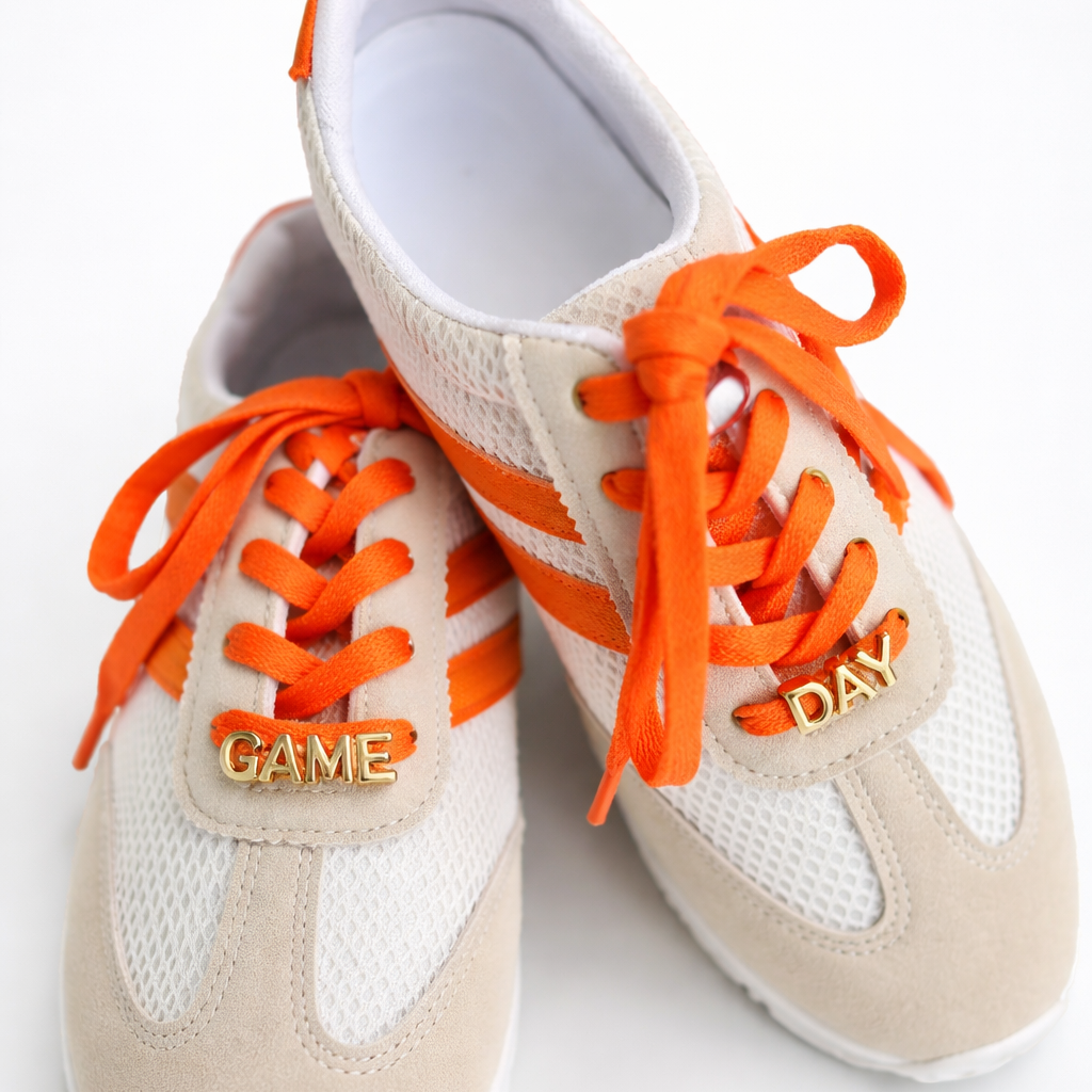 Beige sneakers with orange laces on a white background