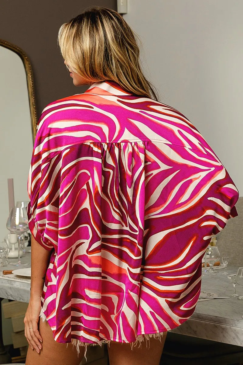 Woman wearing a vibrant pink and orange patterned kimono-style garment in a room setting.