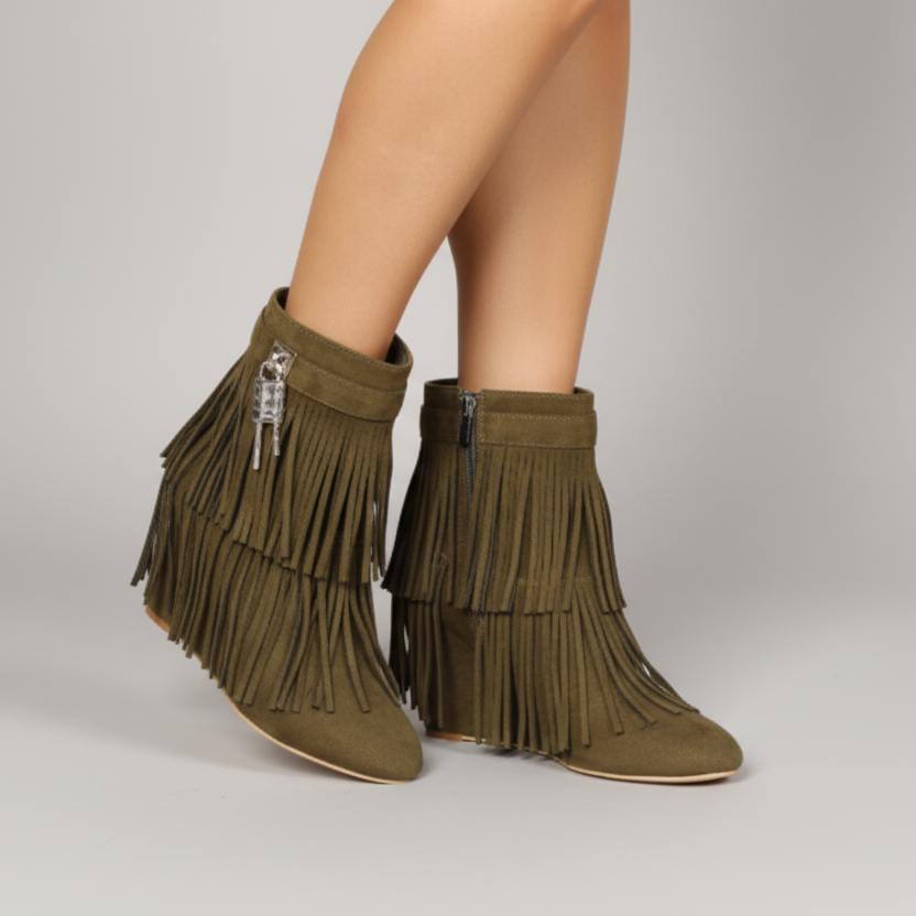 Green fringe boots worn by a person on a neutral background