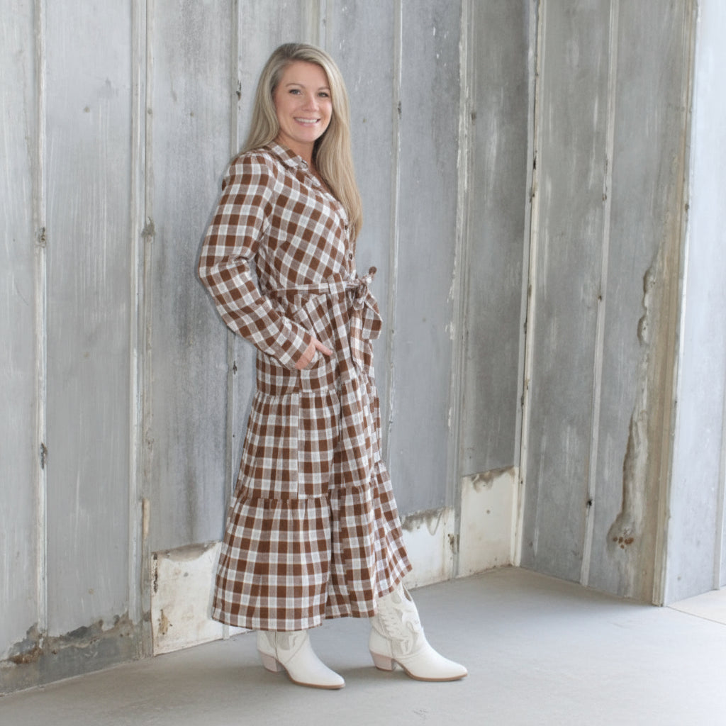 Woman in a checkered dress standing on a wooden deck.