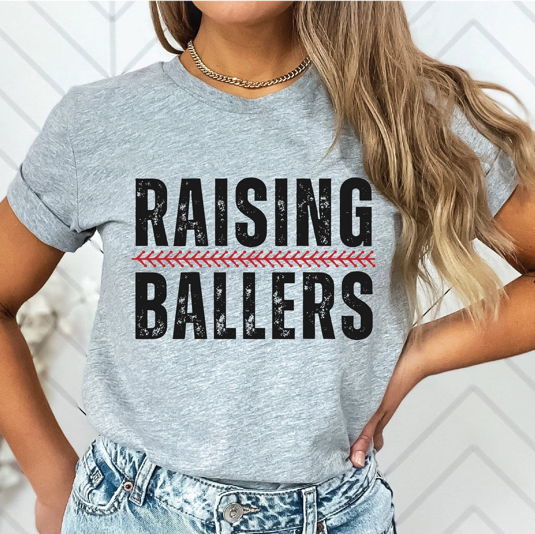 Person wearing a gray t-shirt with 'RAISING BALLERS' text design.