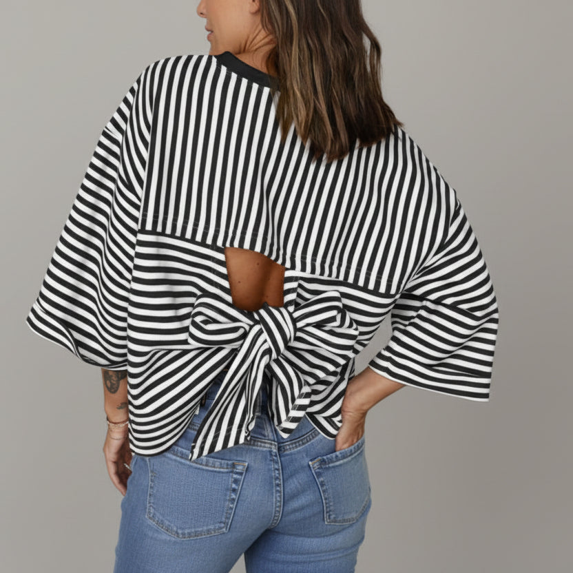 Person wearing a black and white striped top with a knot detail and blue jeans.
