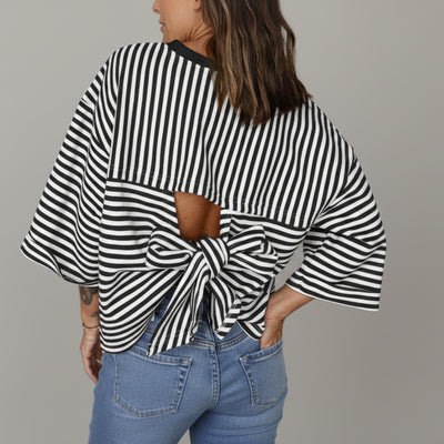 Person wearing a black and white striped top with a knot detail and blue jeans.