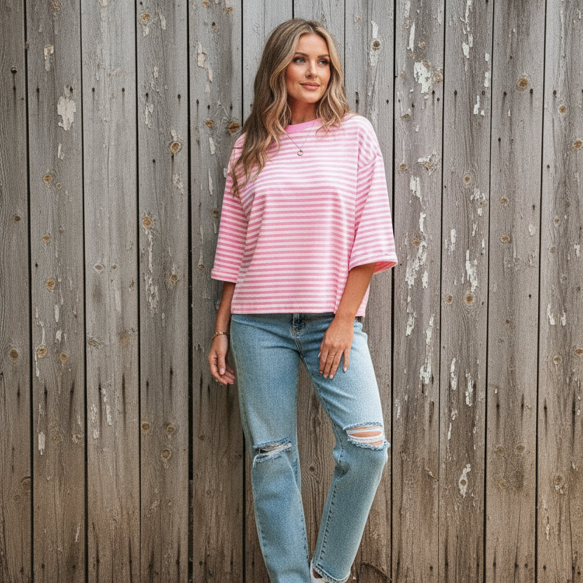Woman wearing a pink and white striped shirt with blue jeans outdoors.