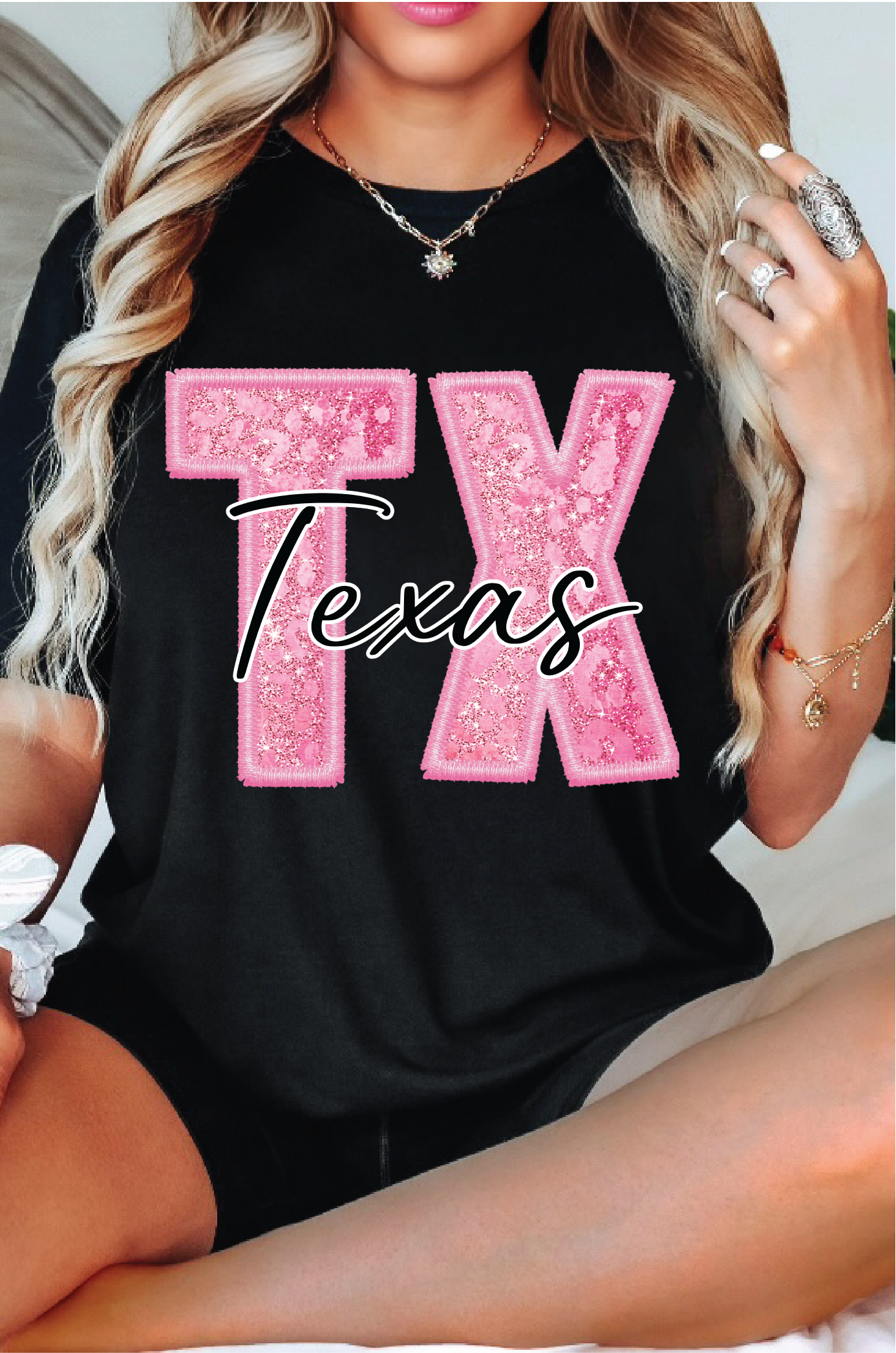 Person wearing a black t-shirt with pink 'TX Texas' design.