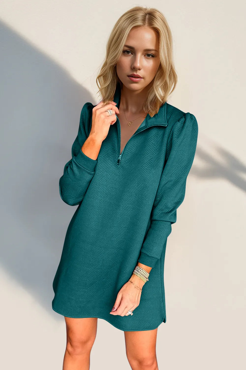 Woman wearing a teal dress against a plain background