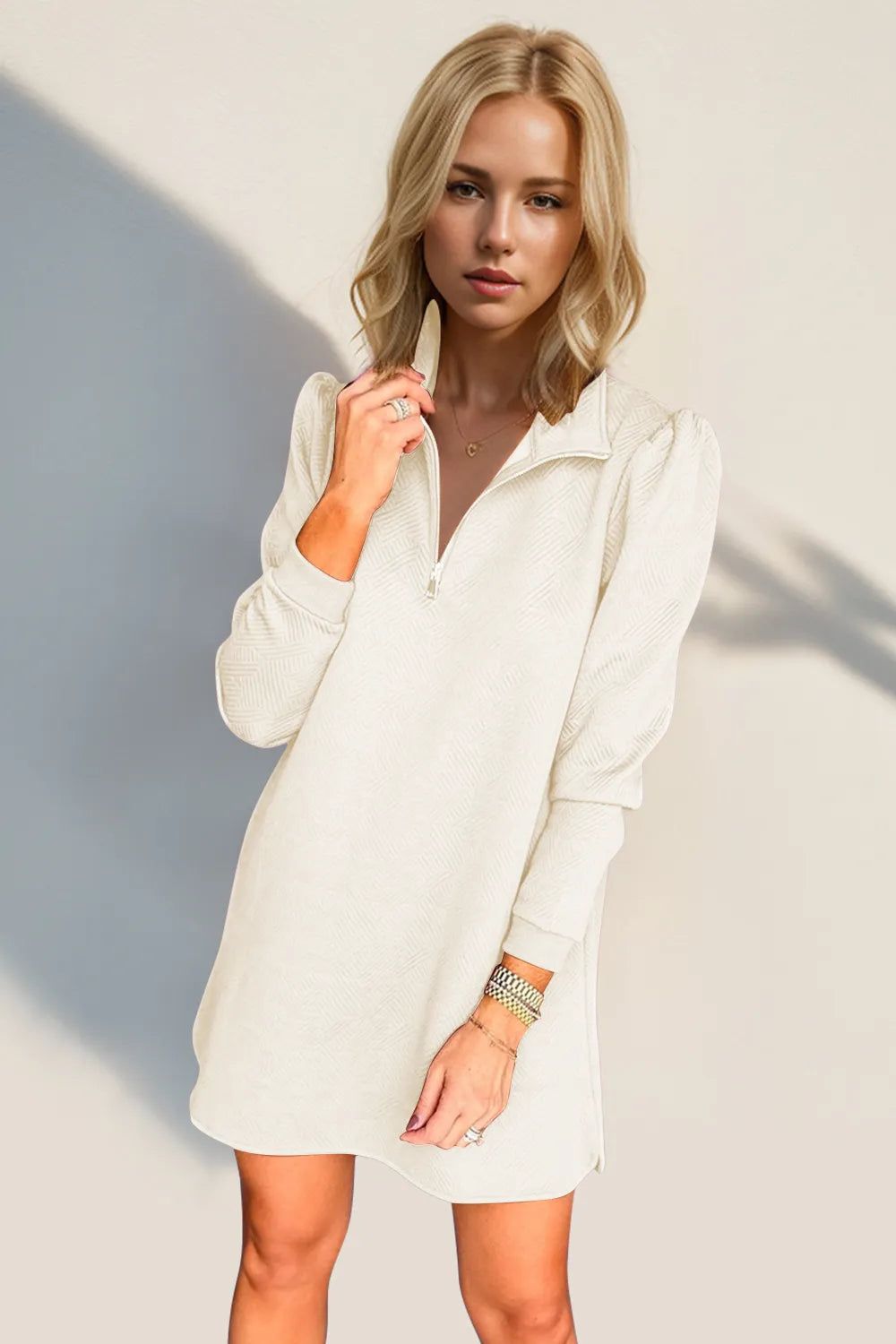 Woman wearing a white shirt dress against a neutral background