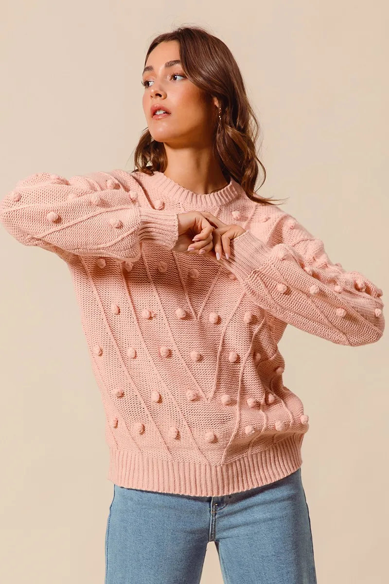 Woman wearing a pink textured sweater with blue jeans on a beige background